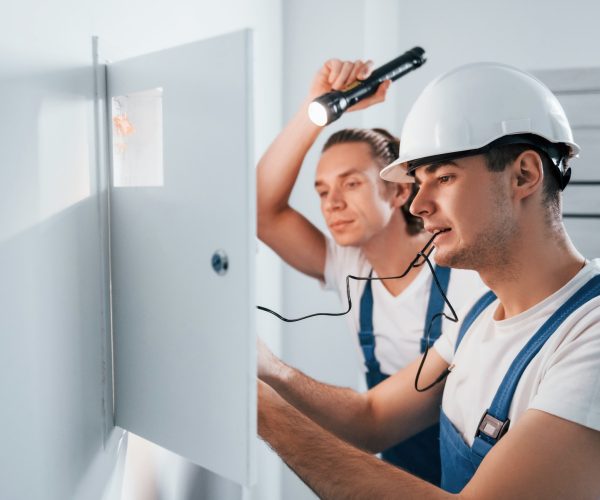 two-young-male-electricians-works-indoors-together-using-flashlight.jpg